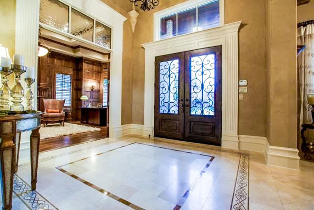 House plan interior foyer with double doors, decorative glass, and wood-paneled room visible beyond.