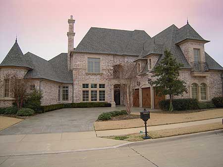 House plan exterior of a two-story brick home with a steep roofline, prominent chimney, and attached three-car garage.