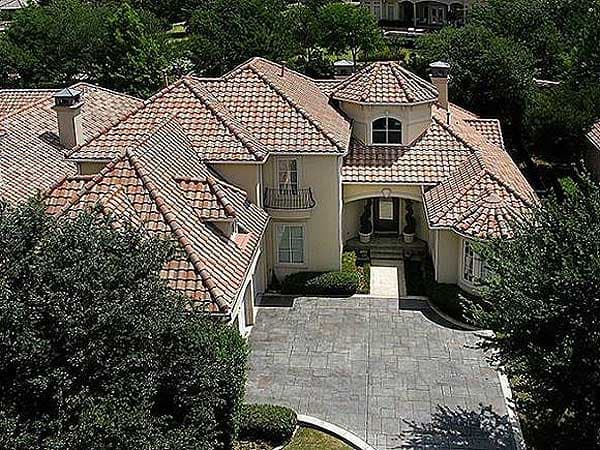 House plan exterior: Mediterranean style, two stories, red tile roof, arched entryway, round turret, and balcony.