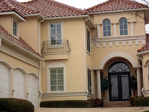 House plan exterior: Mediterranean style, two stories, arched entryway, wrought iron double doors, balcony, and arched garage doors.