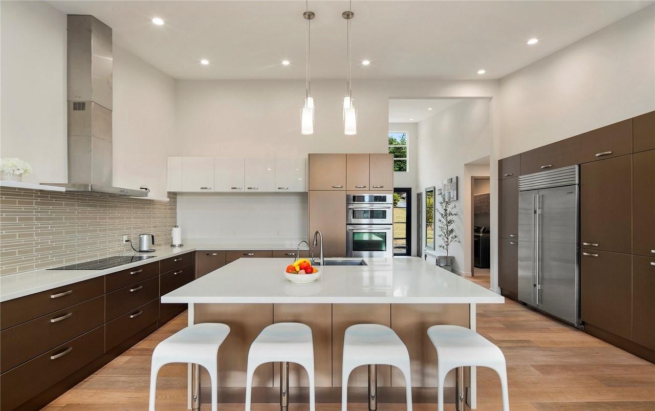 Modern kitchen with waterfall island, stainless steel appliances, mosaic tile backsplash, and ample cabinet storage.