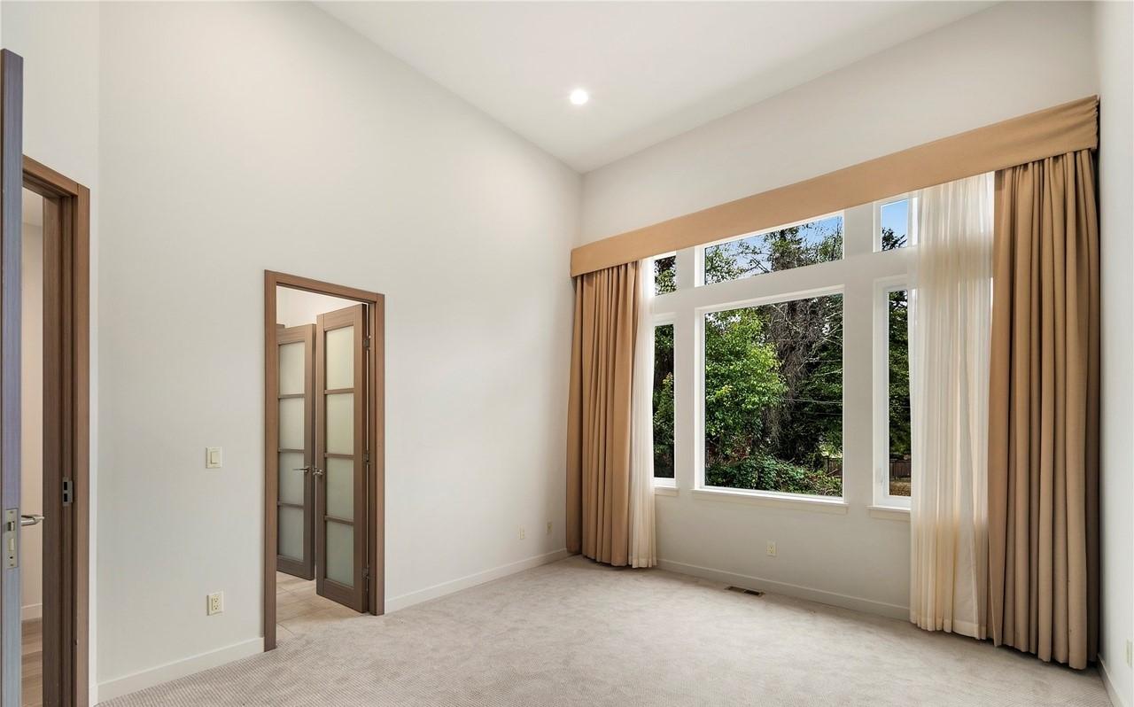 Interior view of room with vaulted ceiling, large windows, and double doors with glass panels.