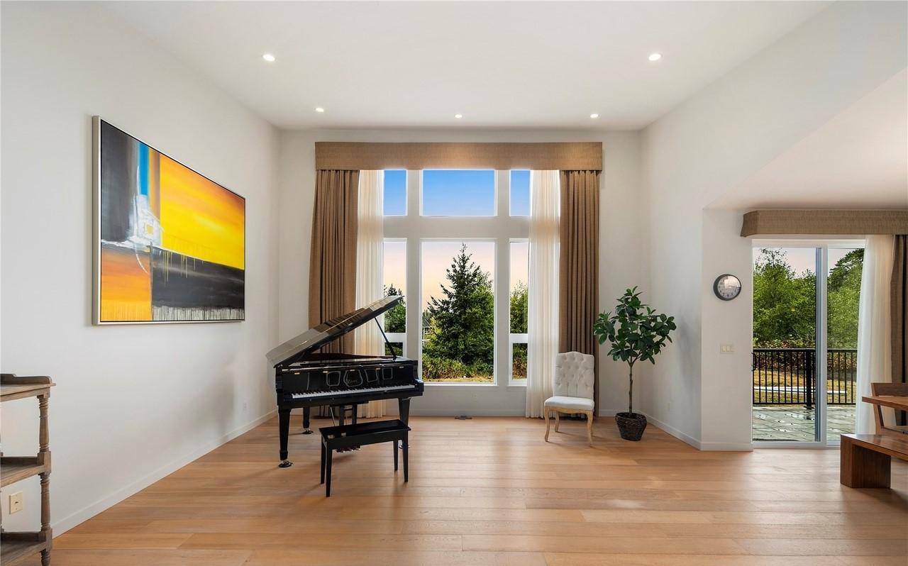 Interior rendering of a great room with a grand piano, large multi-pane windows, and access to an outdoor patio.