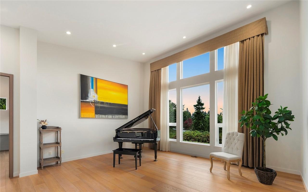 Interior view of a spacious room with a grand piano, large windows, and hardwood floors.