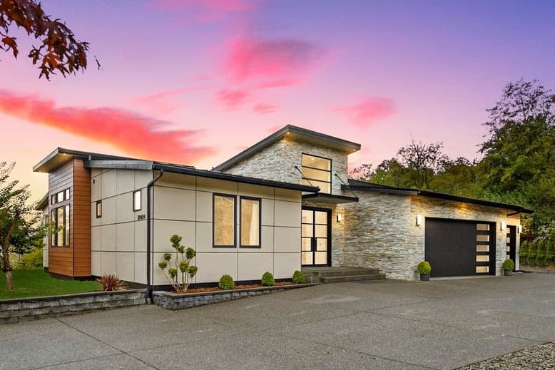 Modern two-story house plan exterior with stone accents, wood siding, multiple gables, and a multi-panel garage door.
