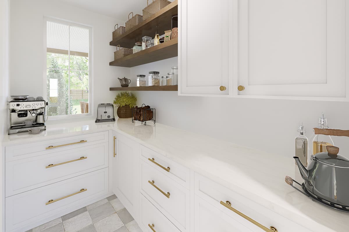 A modern, bright kitchen with white cabinets, gold hardware, and a marble countertop. A coffee machine, toaster, and kettle are on display.
