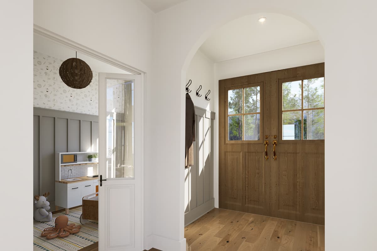Interior view of a hallway leading to a kids' play area. A wooden door with glass panels sits across from a partially open door to the play space.