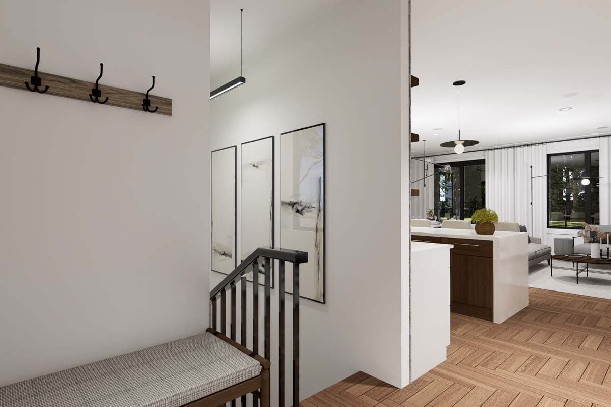 Interior view of a home entrance with a bench, coat rack, staircase, and view into the kitchen and living area.