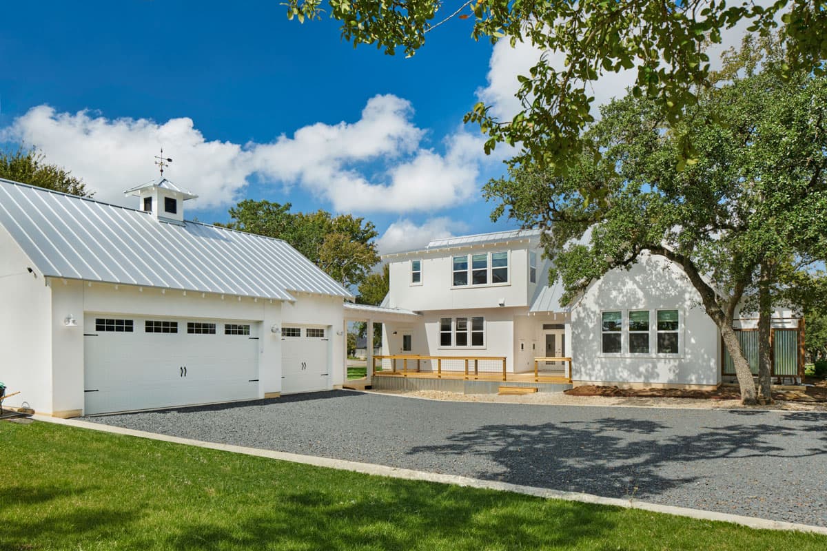 Modern Farmhouse house plan exterior with metal roof, two-car garage, second-story balcony, and white clapboard siding.