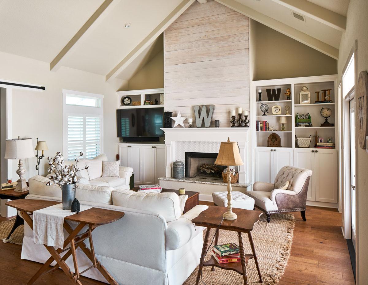 Great room with vaulted ceiling, fireplace with wood plank accent, and built-in shelving.