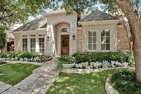 House plan exterior: One-story brick home with arched entry, multi-pane windows, and hip roof.
