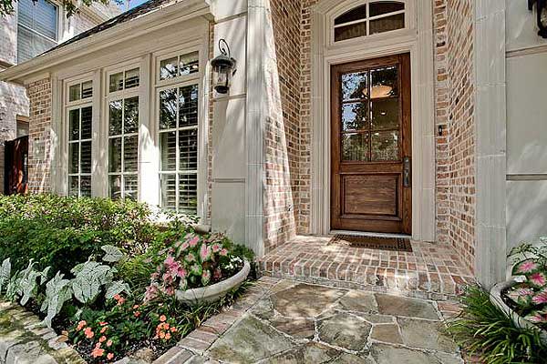 House plan exterior: Brick facade with stone accents, multi-pane windows, arched wooden door with transom, and brick porch.