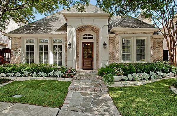 House plan exterior: One-story brick home with arched entry, multi-pane windows, covered porch, and gabled roof.
