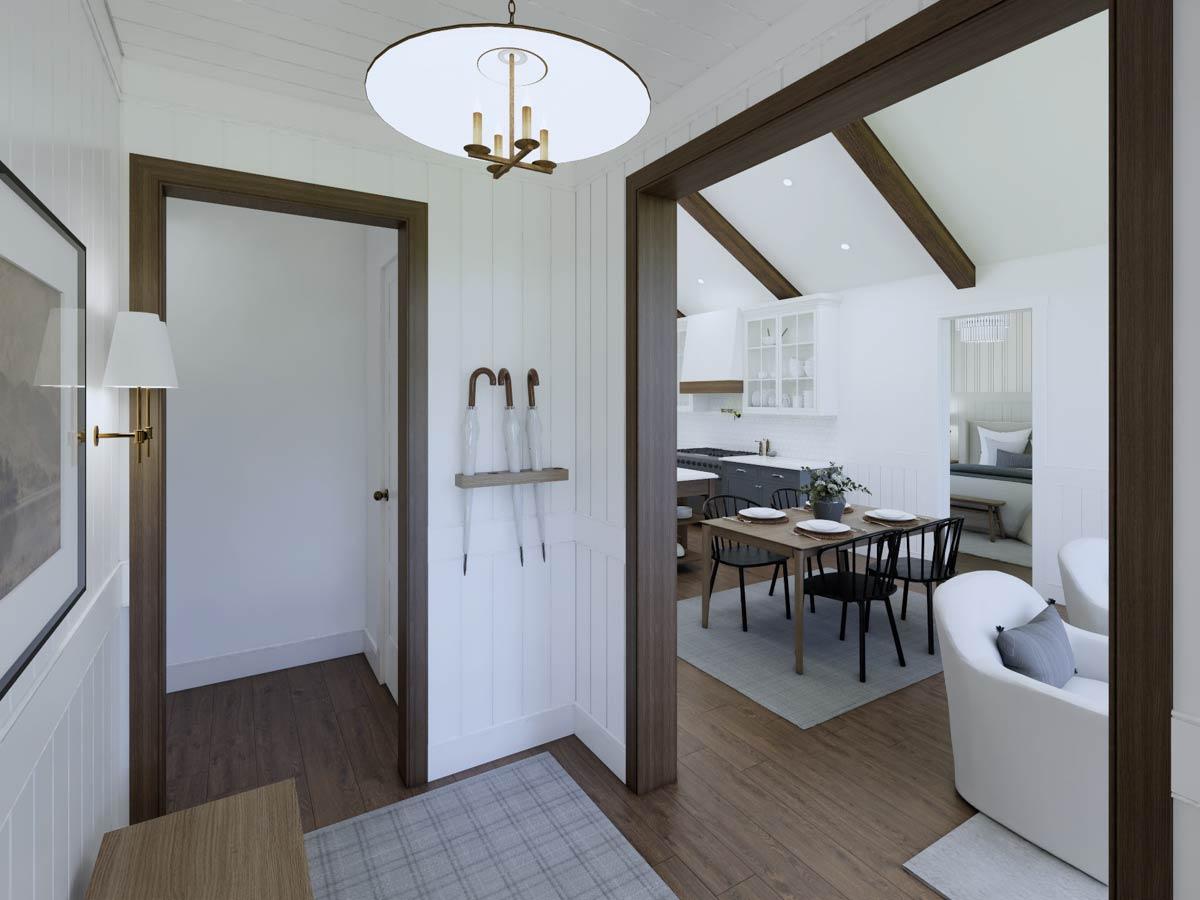 Interior view of a hallway leading to a kitchen and dining area. A white armchair sits near a doorway, visible beyond the dining space.
