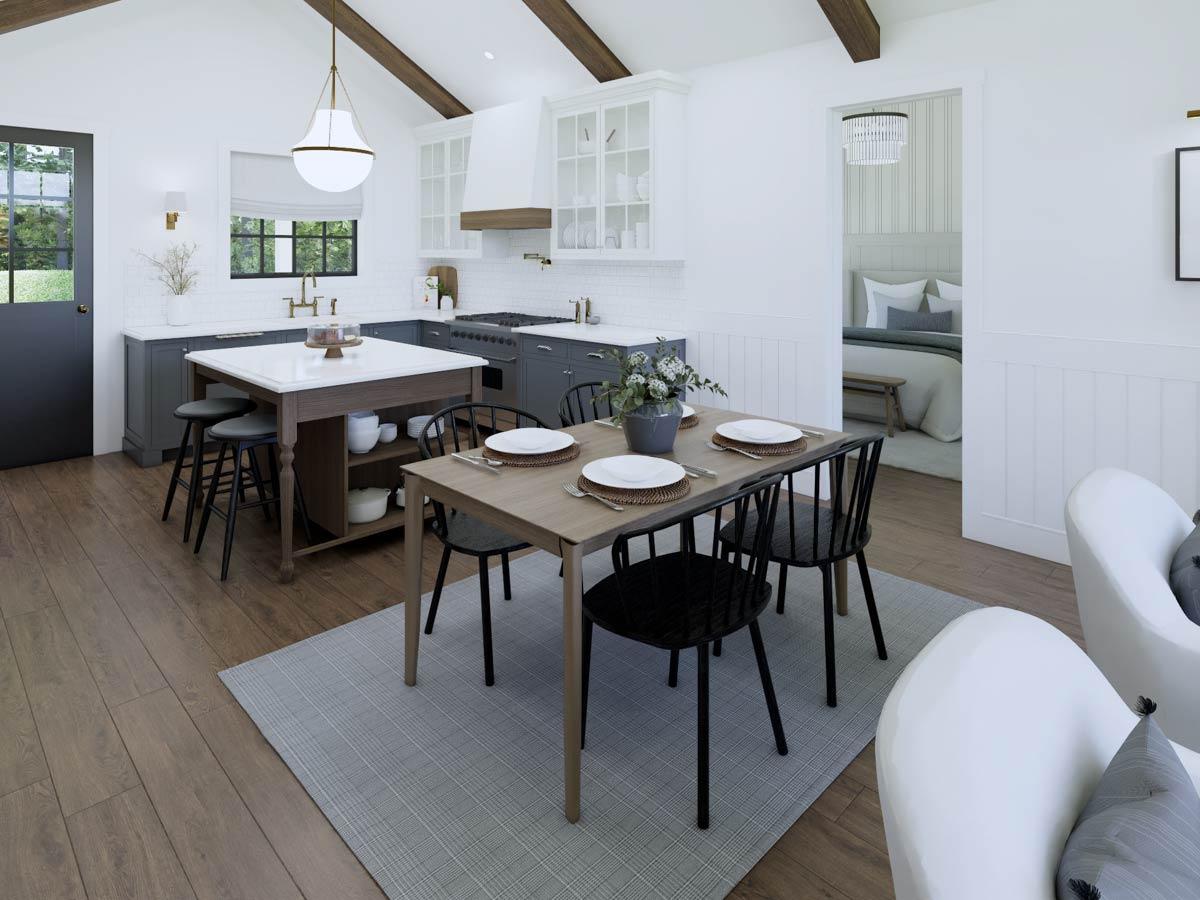 A modern, open-plan kitchen and dining area features a central island, a dining table with place settings, and a glimpse of a bedroom beyond.