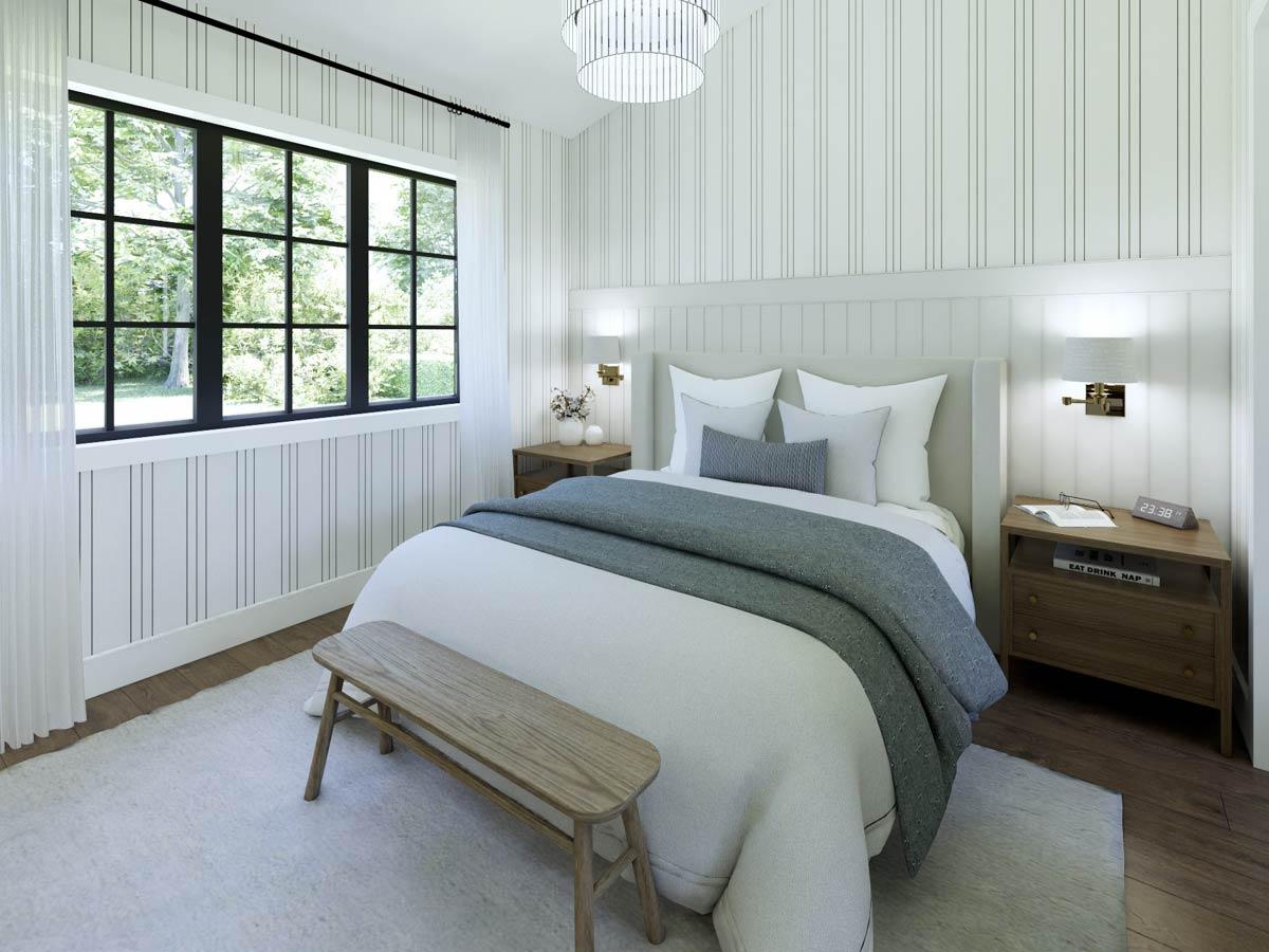 Cozy bedroom with a large window overlooking a lush green space. Features include a bed with layered pillows and a wooden bench at the foot.