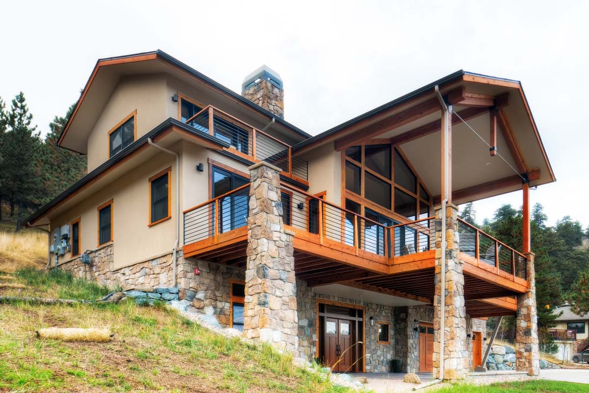 House plan exterior: Modern home with stone base, multi-level decks, wood beams, and large upper-level windows.