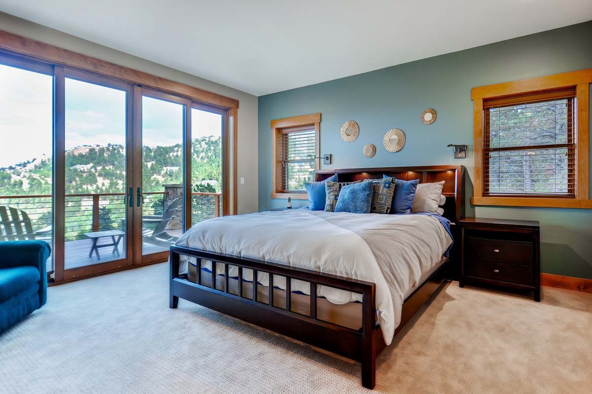 Bedroom with king bed, sliding glass doors to deck, and wood-trimmed windows.