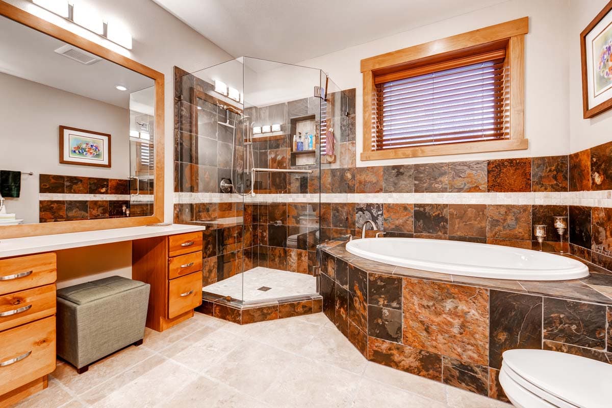 Bathroom with corner glass shower, oval soaking tub, dual vanity, and wood cabinetry.
