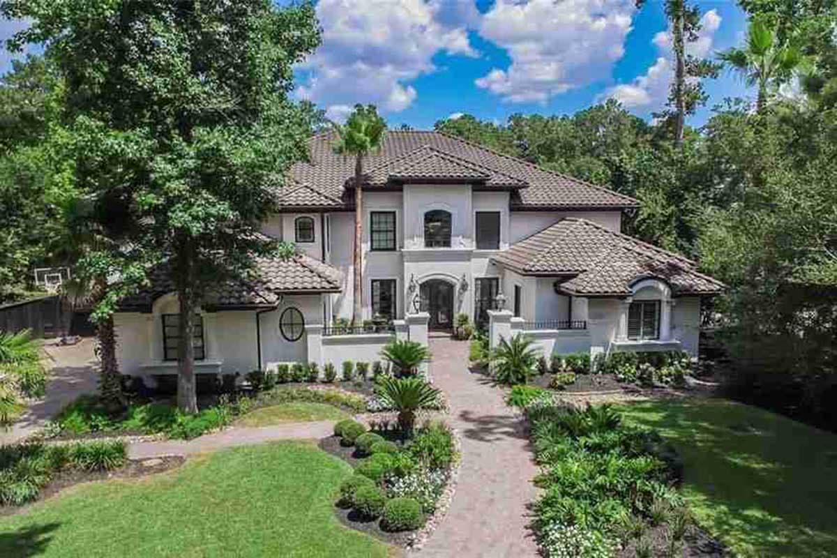 House plan exterior: Two-story stucco home with tile roof, arched entry, and multiple gables.