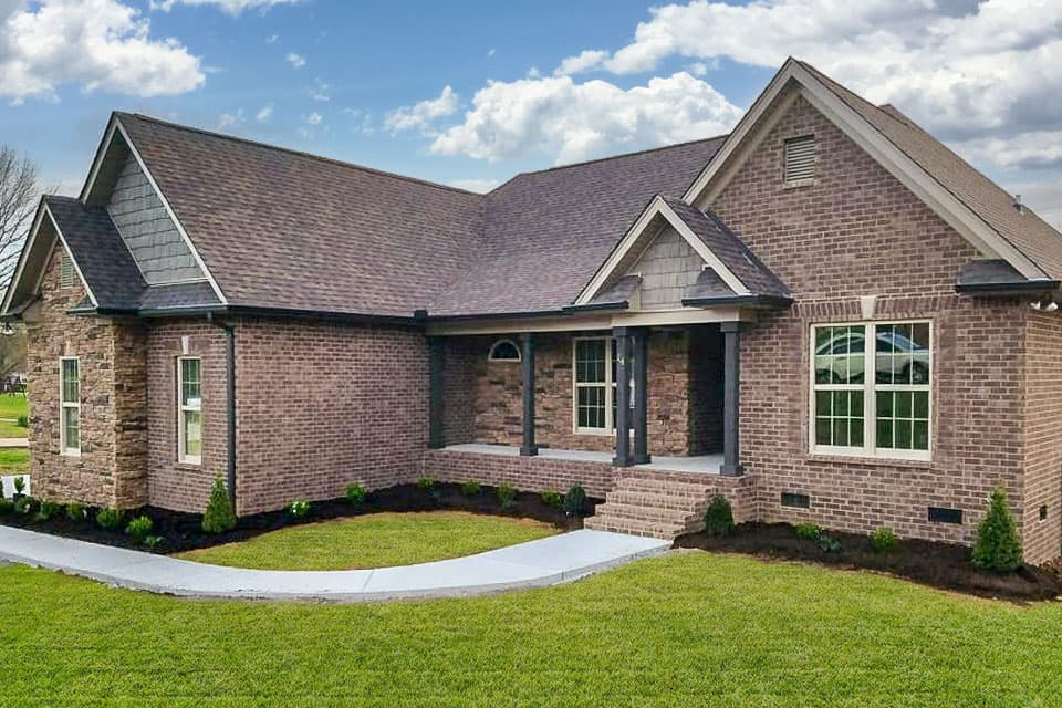 House plan exterior with brick facade, front porch with columns, gabled roof, and multiple dormers.