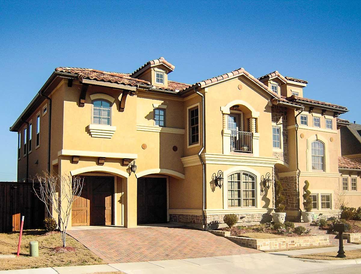 House plan exterior. Two-story Mediterranean-style home with a tile roof, arched garage openings, and second-floor balcony.