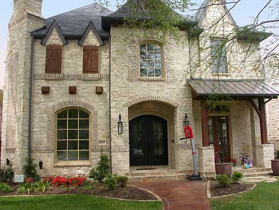 House plan exterior: Two-story stone home with arched entry, metal porch roof, and dormer windows.