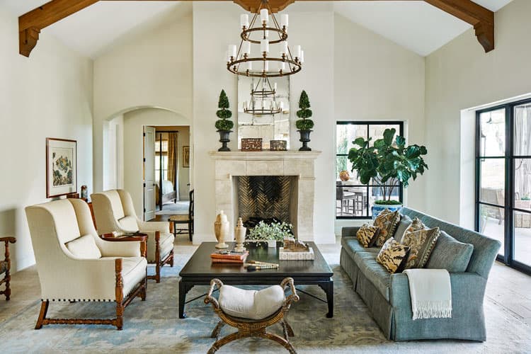 Living room with vaulted beamed ceiling, stone fireplace with herringbone firebox, and adjoining archway to hallway.