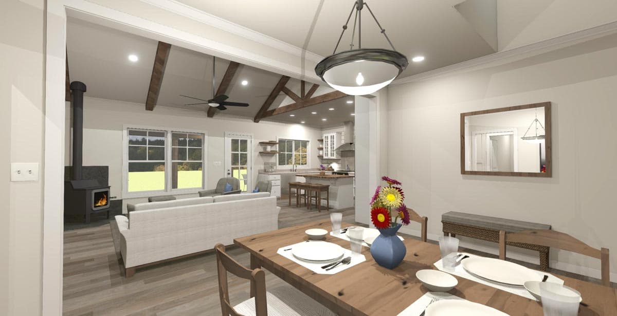Open concept living area with a wood stove, large windows, vaulted ceiling with exposed beams, and kitchen with island.