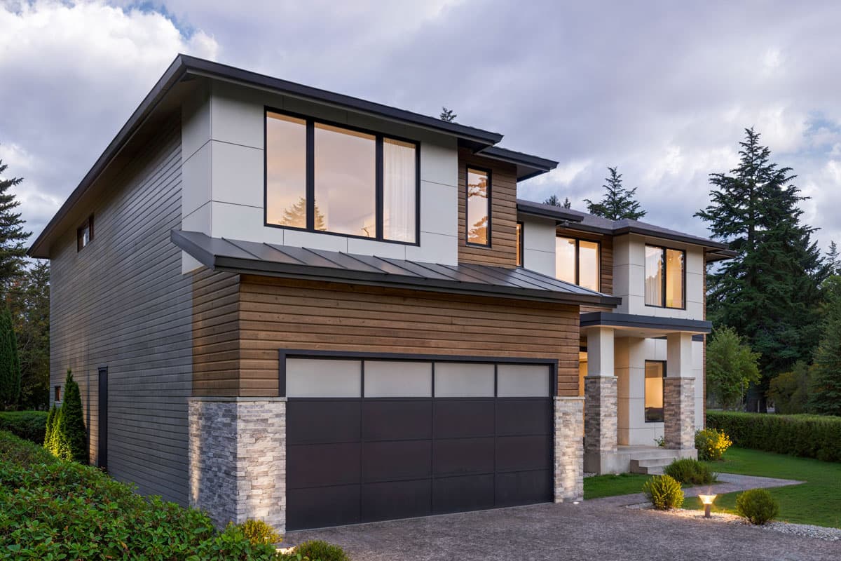 Two-story Modern Farmhouse exterior with horizontal siding, stone accents, a metal roof, and a segmented garage door.