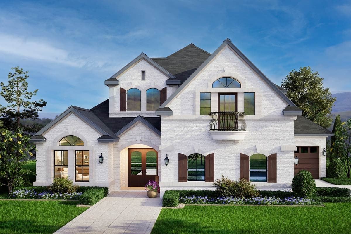 House plan exterior. Two-story home with a gabled roof, arched windows, shutters, and a balcony. Stone exterior and attached garage visible.