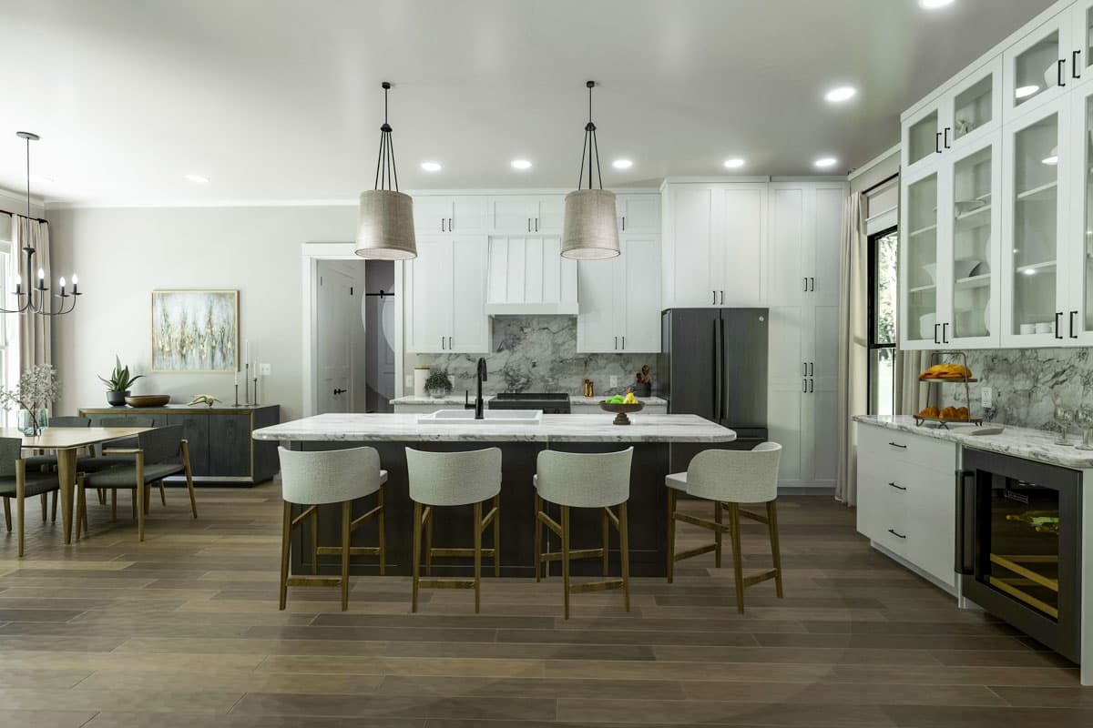 Kitchen with island, white cabinets, dark refrigerator, dining area, and marble backsplash.