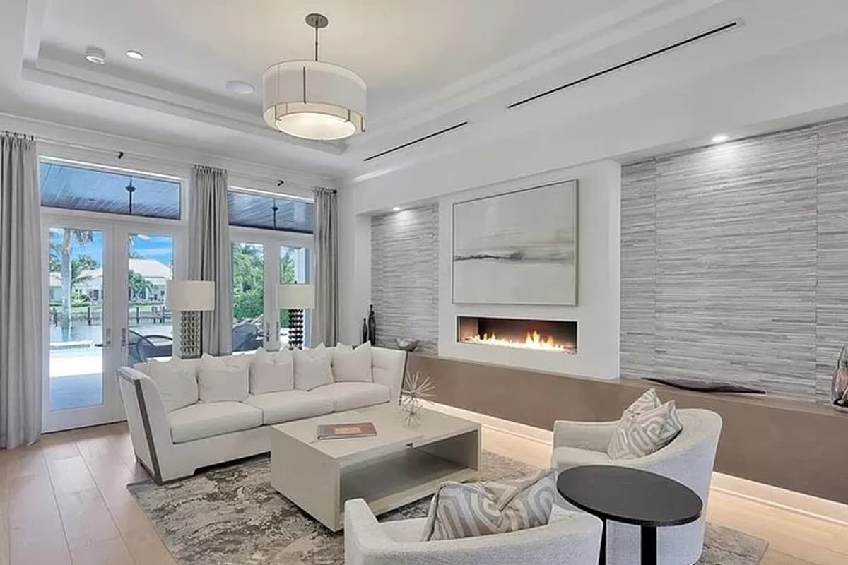 Modern living room with large windows, gas fireplace, contemporary sofa, and accent wall.
