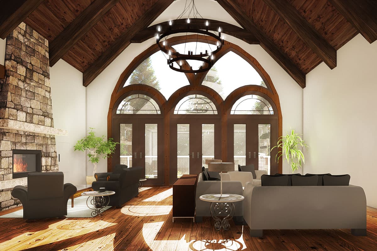 Living room with vaulted wood-beamed ceiling, stone fireplace, and arched French doors.