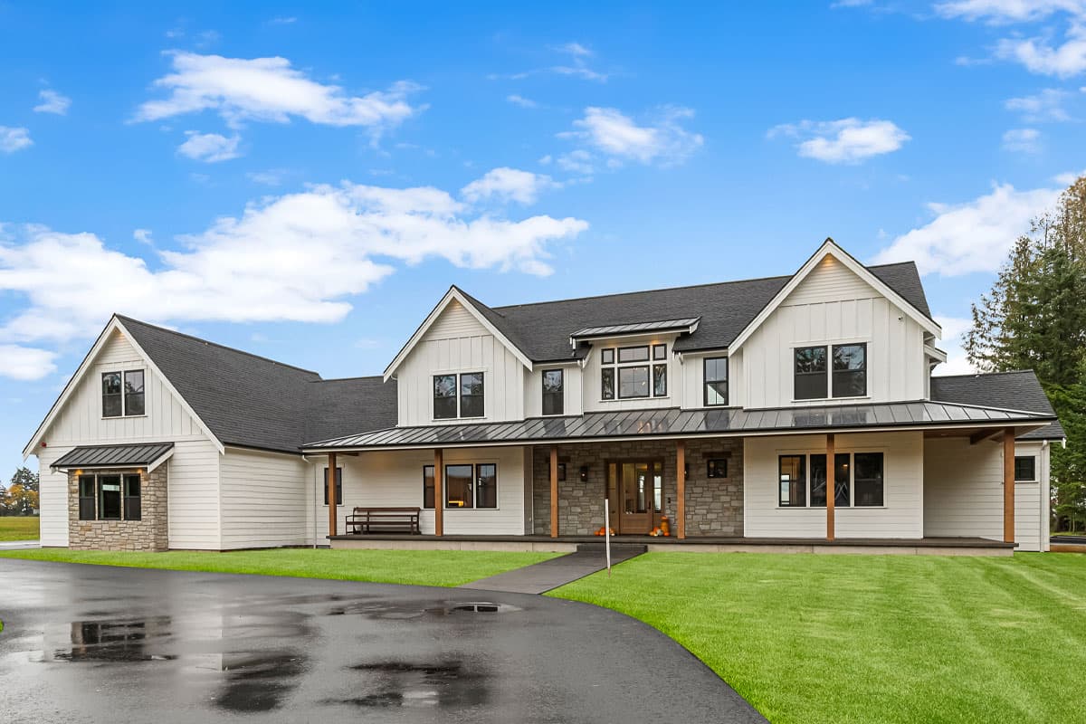 House plan exterior. Two-story Modern Farmhouse with a covered porch, gabled roof, and stone accents at entry. Features a dark asphalt roof.