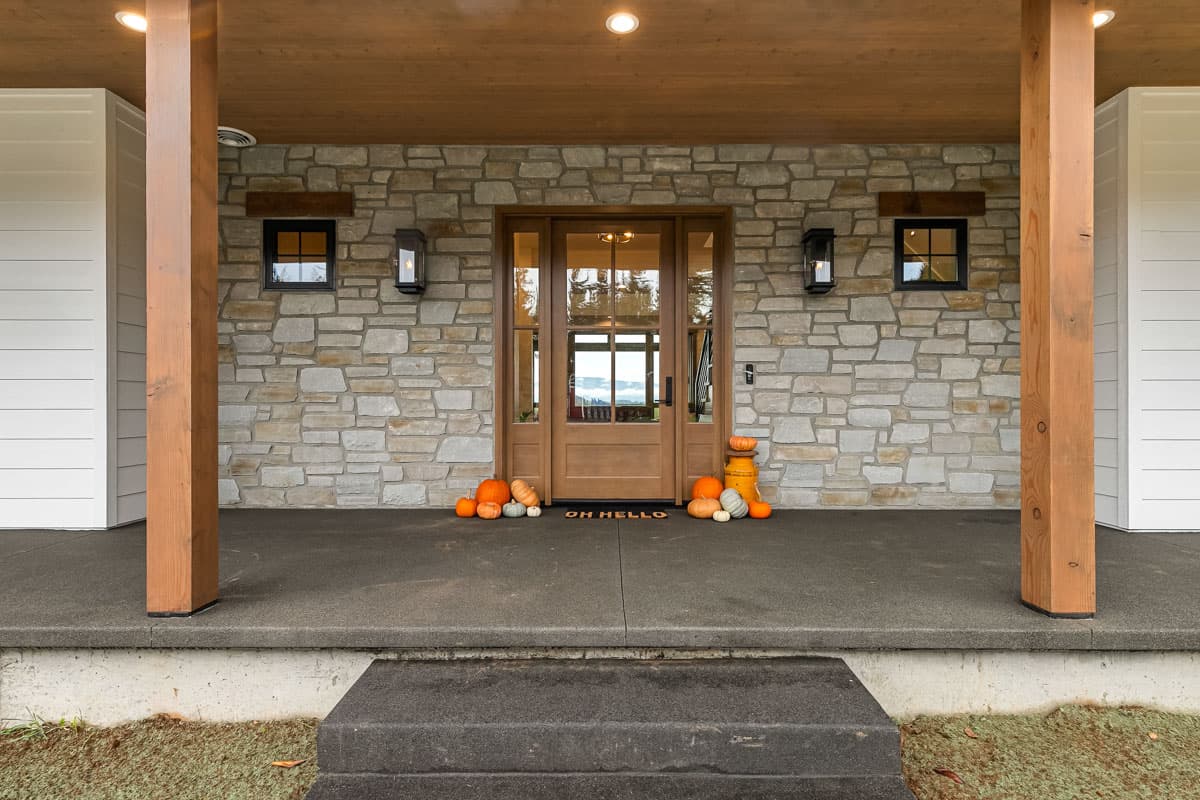 House plan exterior with stone facade, wood-framed front door, porch with wood columns, and siding.