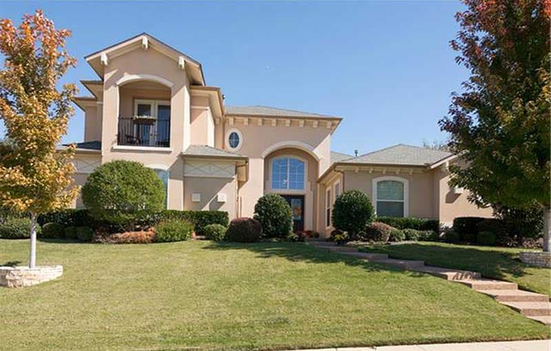 House plan exterior: Two-story Mediterranean style with arched entryway, balcony, and multi-level rooflines.