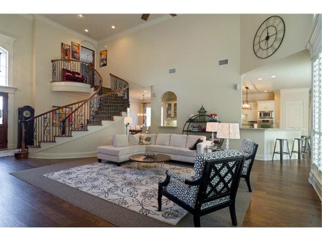 Interior view of a two-story living room with a grand spiral staircase, open concept to the kitchen, and vaulted ceilings.