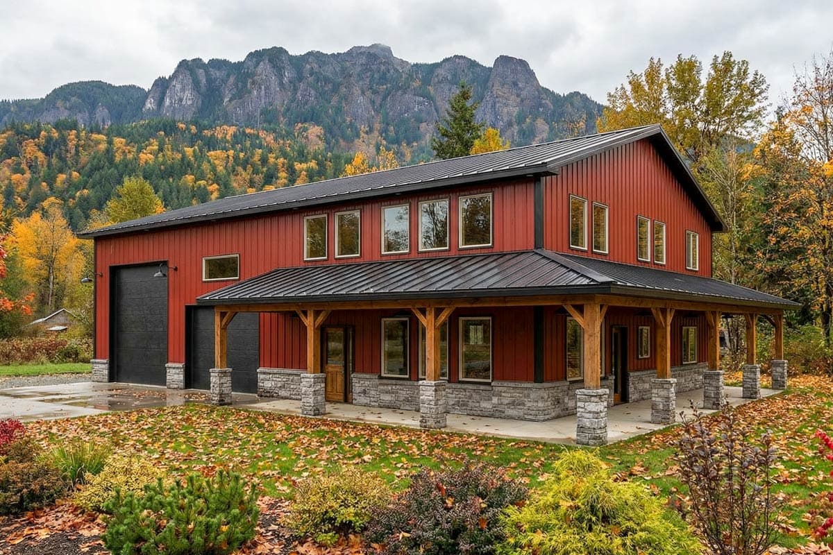 A red, two-story home with a wrap-around porch and a black garage door. Mountains covered in autumn foliage are in the background.