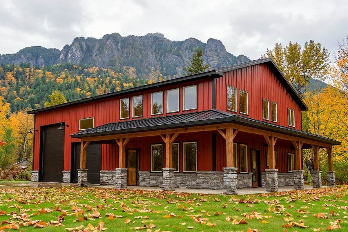 A vibrant red barn-style house with a long porch stands against a backdrop of a mountain covered in autumn foliage, under an overcast sky.