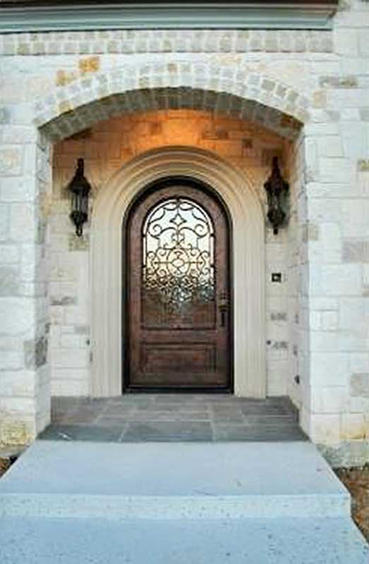 House plan exterior: arched stone entryway with ornate metal-glass door and two exterior sconces.