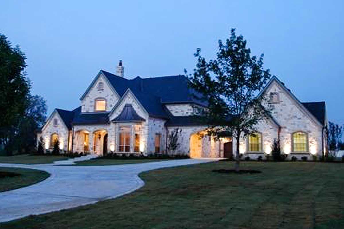 Stone-clad two-story house plan exterior with arched entryway, gables, and pitched rooflines.