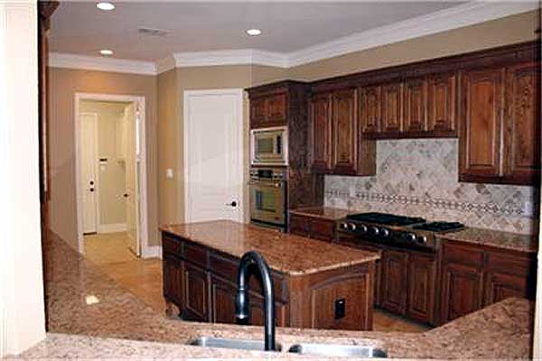 Kitchen with granite island and countertops, dark wood cabinets, stainless steel appliances, and tile backsplash.