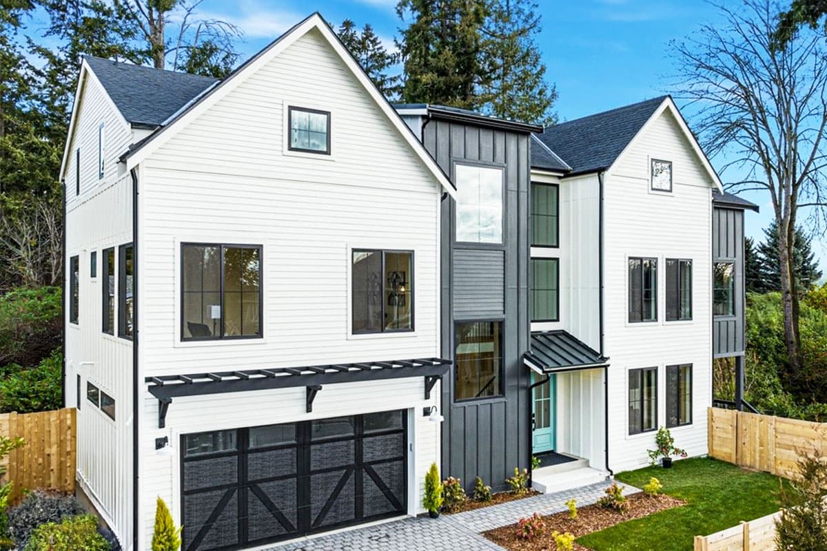 Modern Farmhouse house plan exterior, three stories, white siding, dark metal accents, gabled roof, and attached garage.
