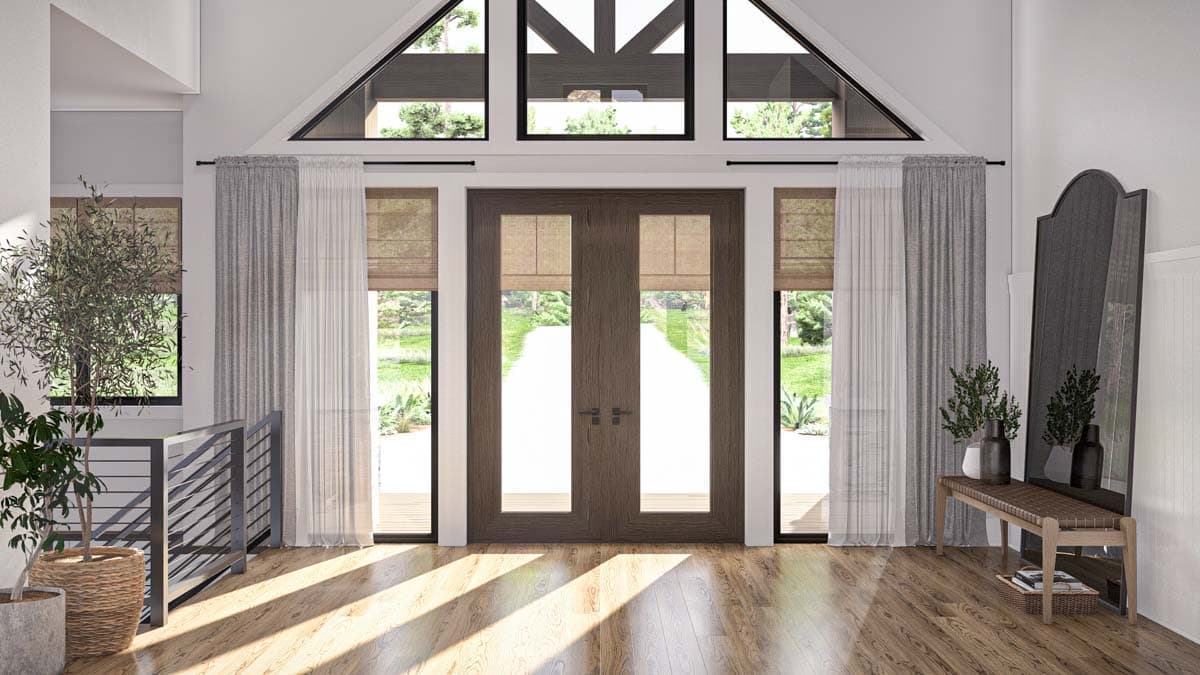 Interior view of entryway with double doors, tall windows, vaulted ceiling with exposed beams, and a modern metal railing.