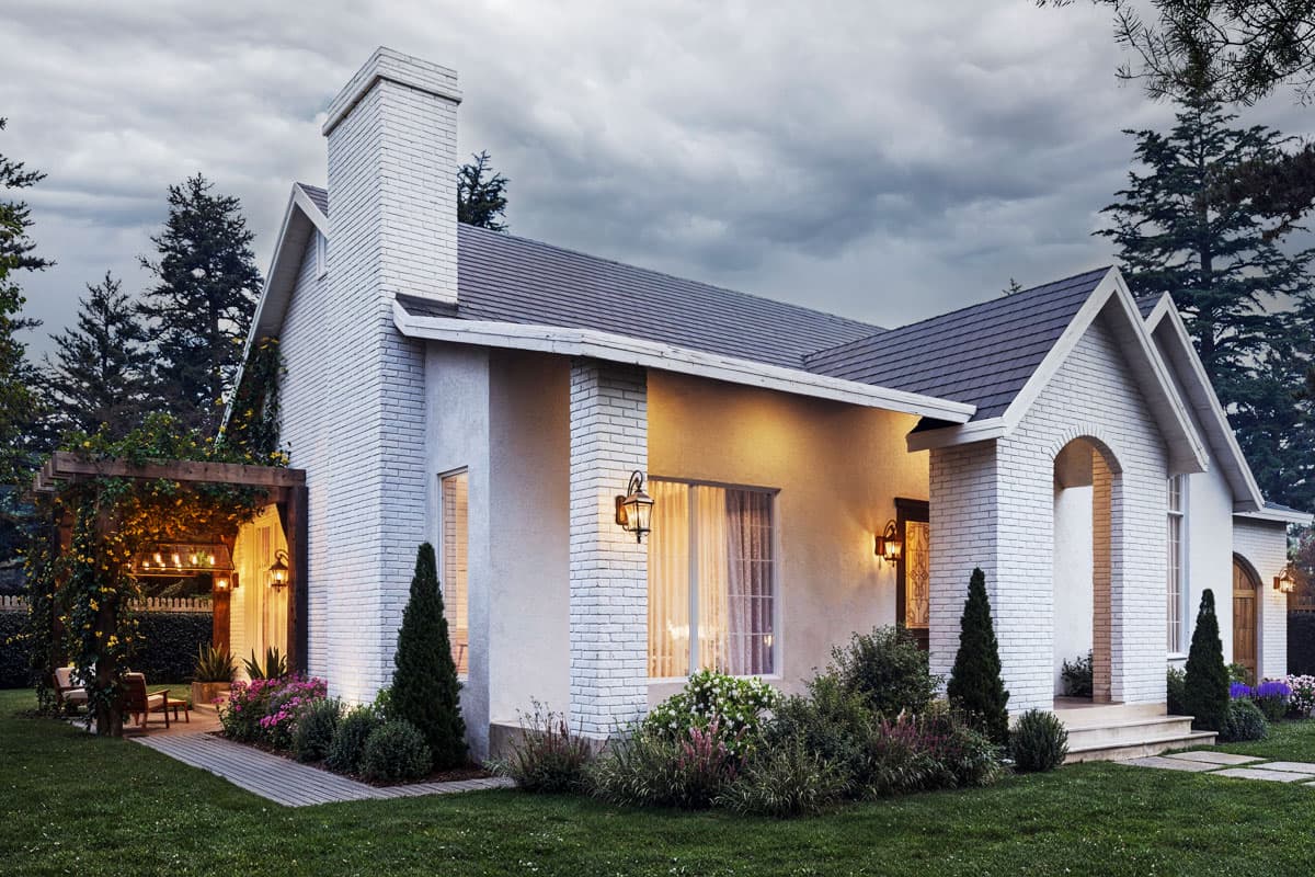 House plan exterior: White brick home with gabled roof, large chimney, covered pergola entry, and arched entryway.