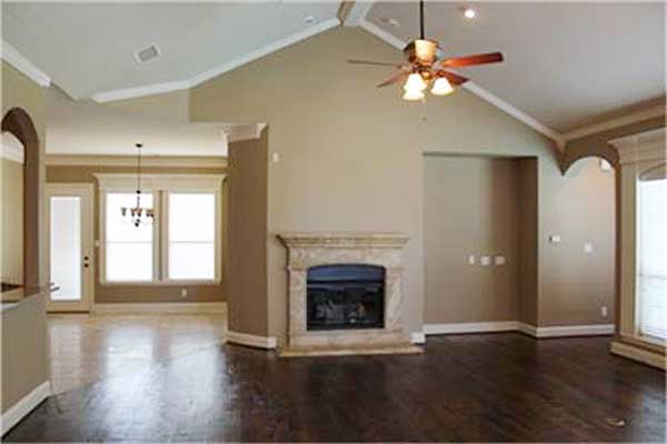 Interior rendering showing a great room with a stone fireplace, vaulted ceiling, ceiling fan, and arched doorways.