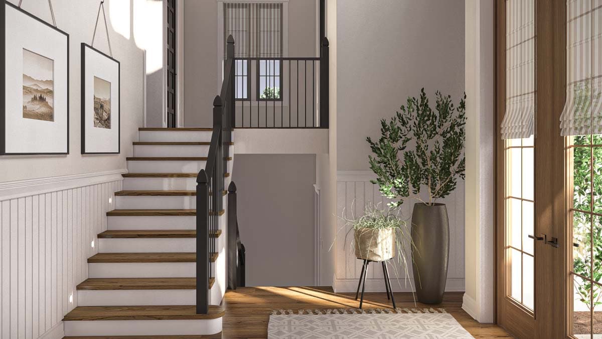 Interior view of a home entryway with a staircase, wainscoting, framed art, and double doors.