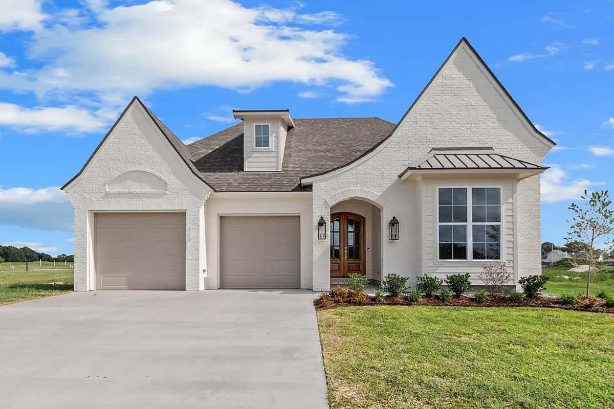 House plan exterior with two-car garage, brick facade, arched entryway, and multiple gables. Features include dormer window and covered window detail.