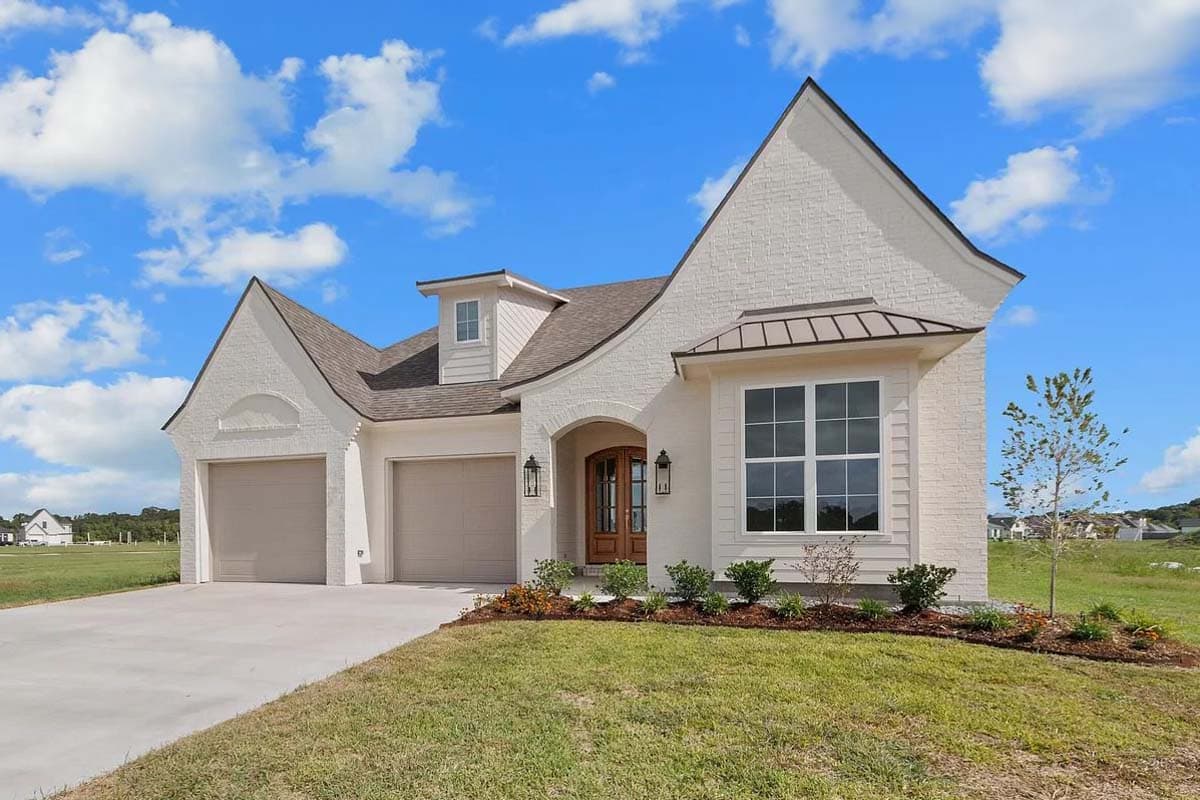 House plan exterior: white brick, dormer, arched entryway, side-entry garage, and metal roof detail.